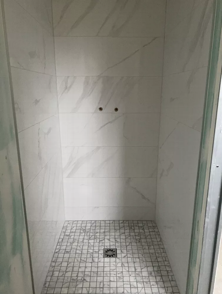 Douche carrelée en carreaux blancs marbrés et sol en mosaïque