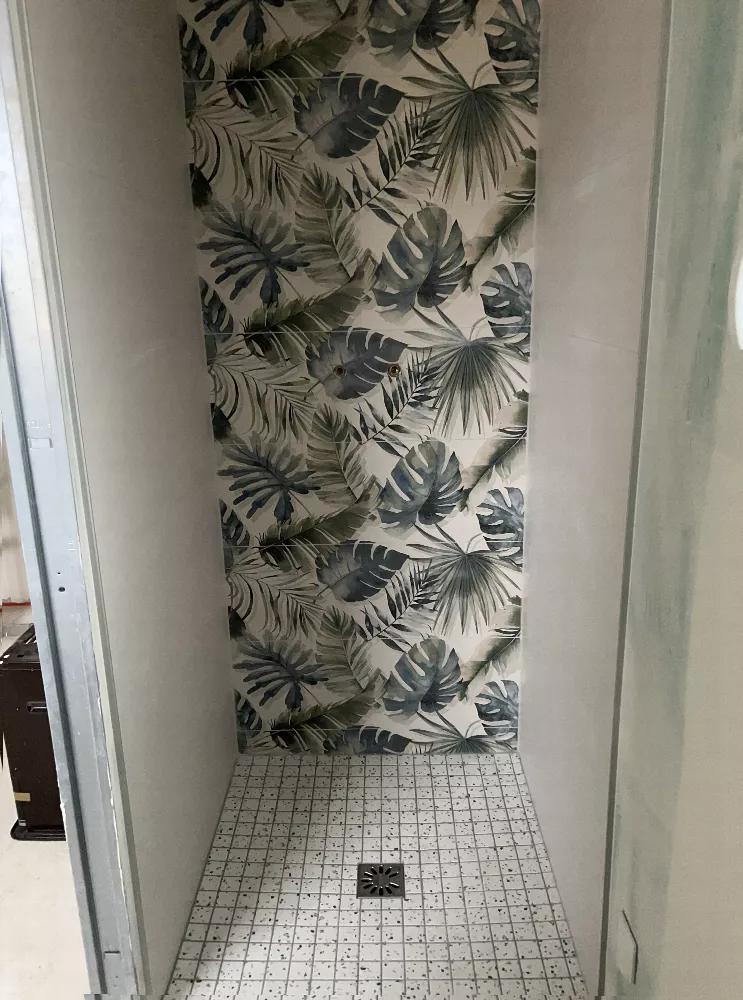 Douche carrelée avec papier peint à motifs de feuilles tropicales