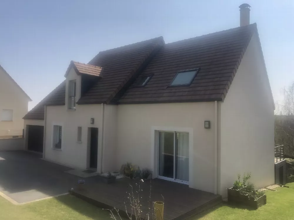 Maison à étage aux enduits clairs et toiture en tuiles brunes, avec terrasse