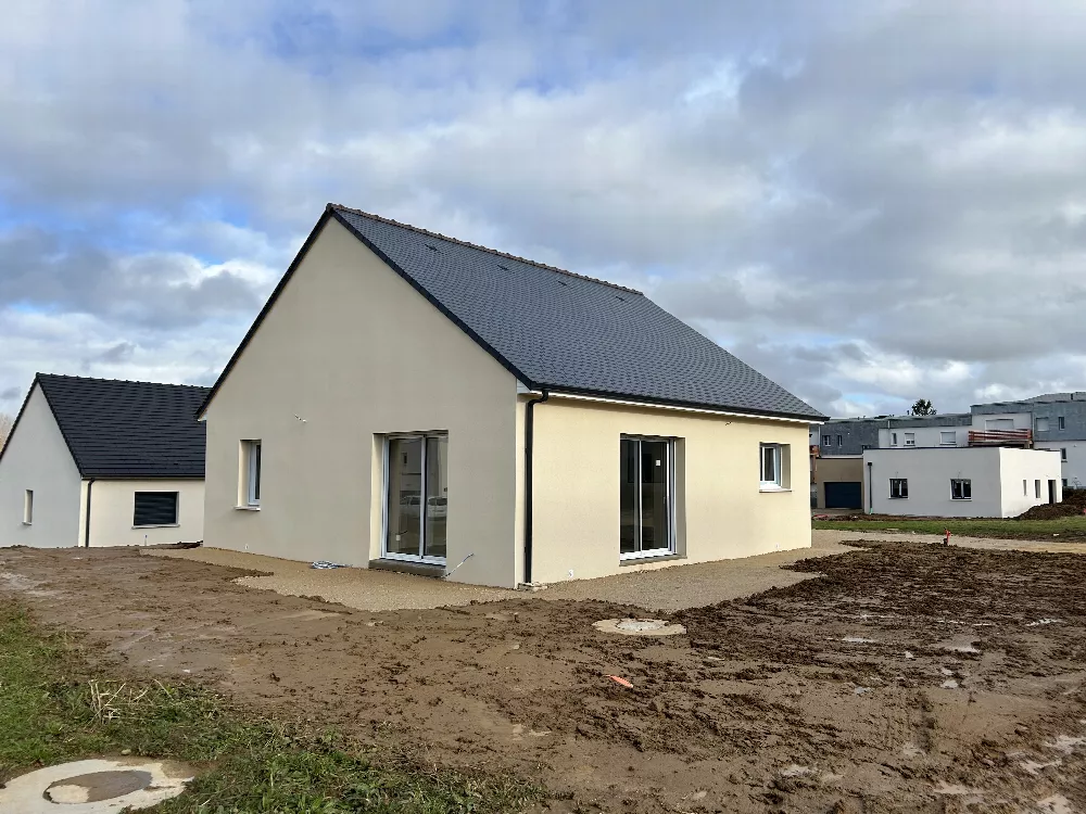 Maison neuve à toit d'ardoises, façade beige, terrain en cours de finition