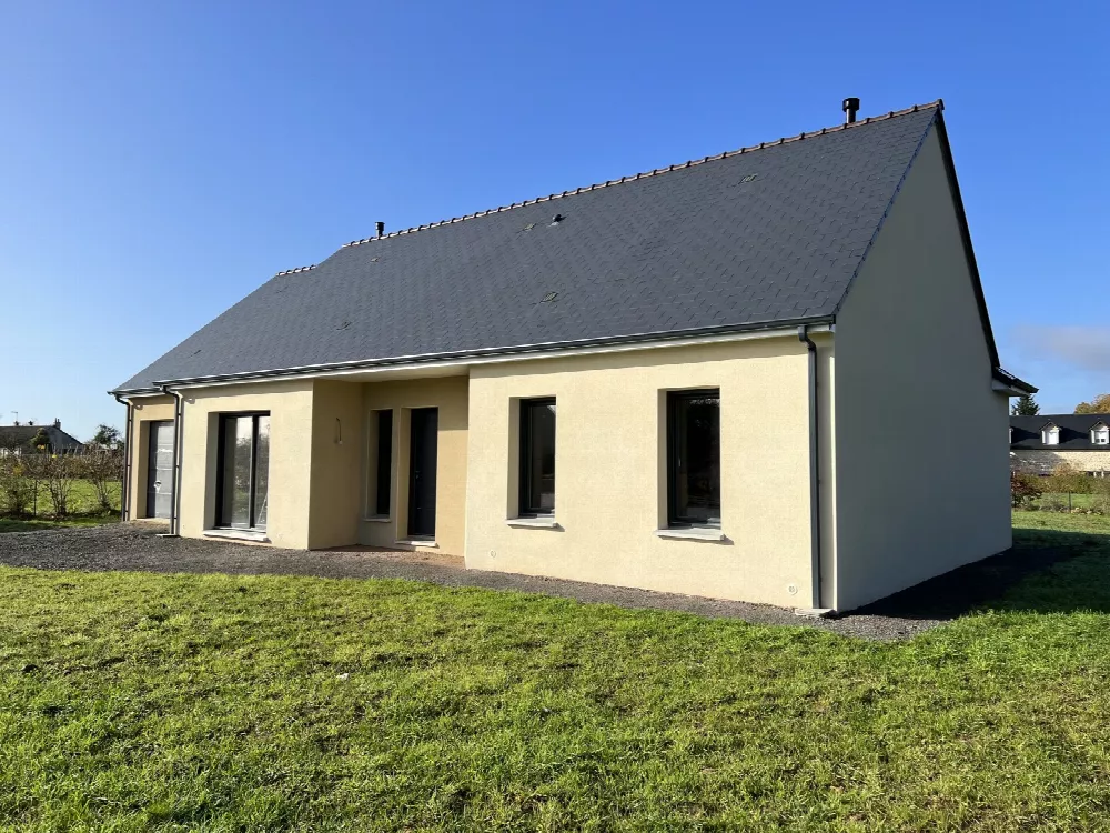 Maison neuve à toit d'ardoises et façade jaune pâle, vue de côté