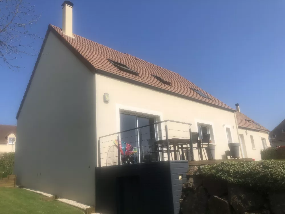 Pignon d'une maison enduite avec balcon et toit de tuiles rouges