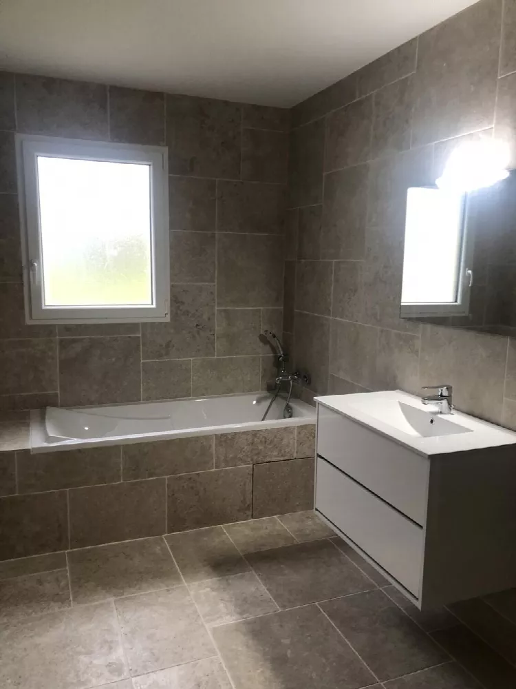 Salle de bain avec baignoire d'angle, meuble vasque et deux fenêtres