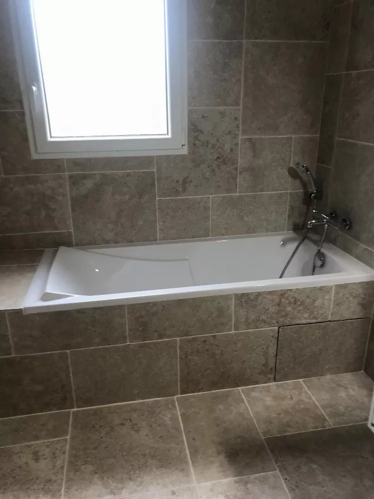 Salle de bain avec baignoire encastrée et carrelage gris