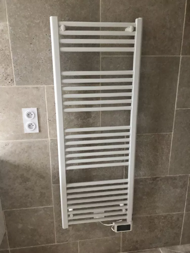 Sèche-serviettes blanc mural dans une salle de bain carrelée